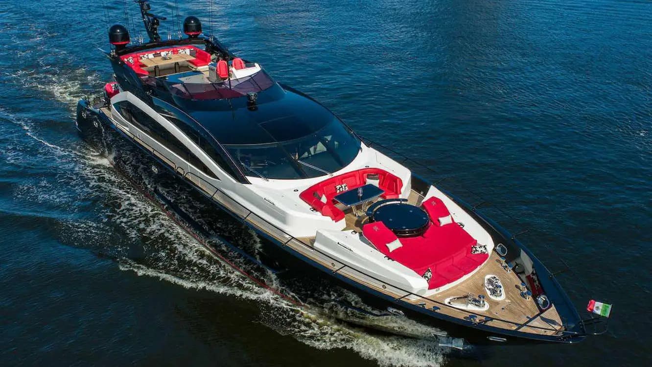Sleek black and white luxury yacht with vibrant red seating cruising through blue water.